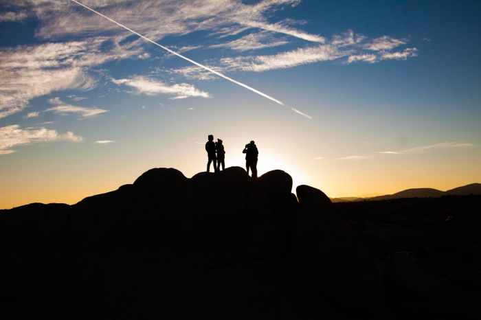 silhouette photo of people on top of rock formation